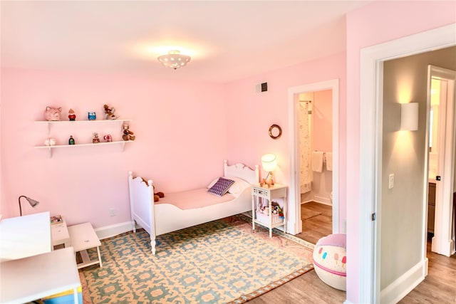 bedroom with visible vents, baseboards, and wood finished floors