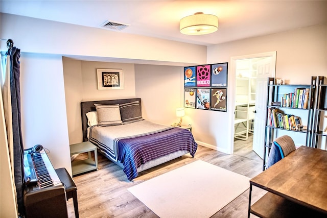 bedroom with visible vents, baseboards, and wood finished floors