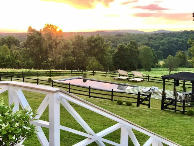 view of gate with a lawn, a mountain view, a forest view, and fence