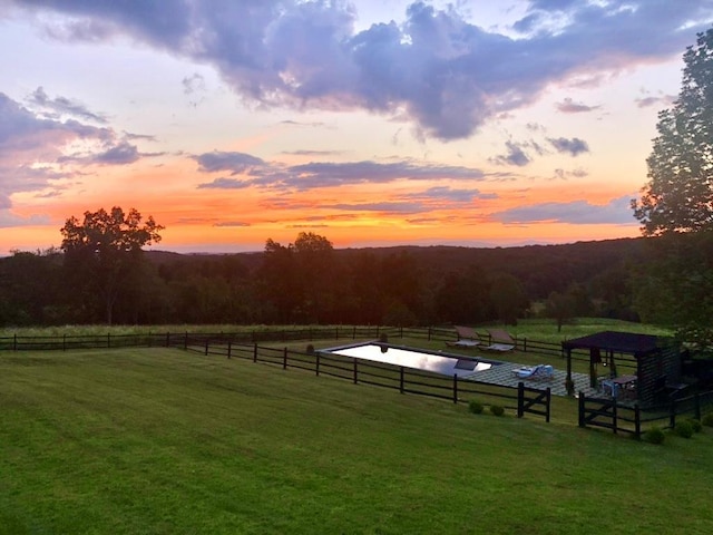 yard at dusk featuring a rural view