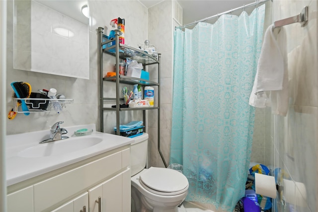 bathroom with tile walls, toilet, curtained shower, and vanity