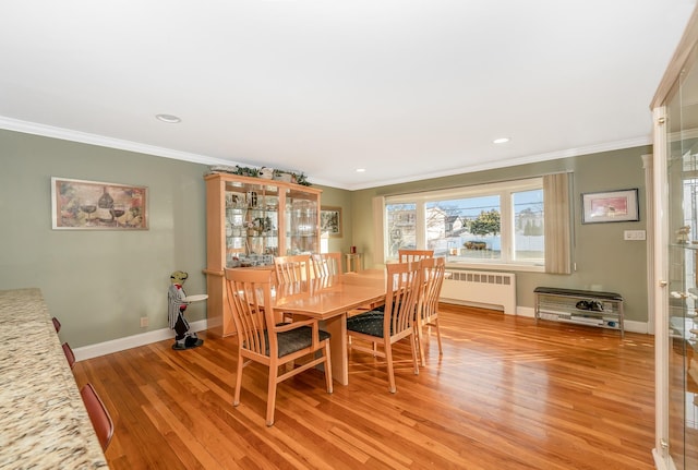 dining area featuring radiator, crown molding, and light wood-type flooring