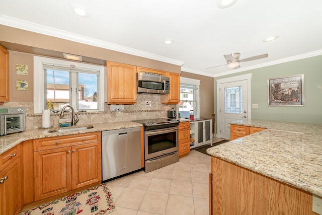 kitchen featuring sink, crown molding, backsplash, stainless steel appliances, and light stone counters