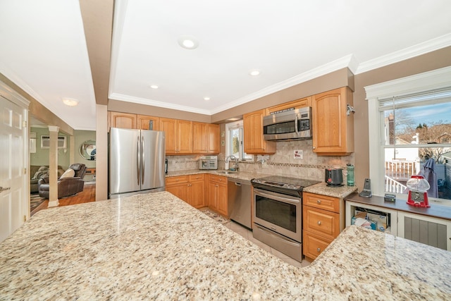 kitchen featuring sink, stainless steel appliances, light stone counters, ornamental molding, and decorative backsplash