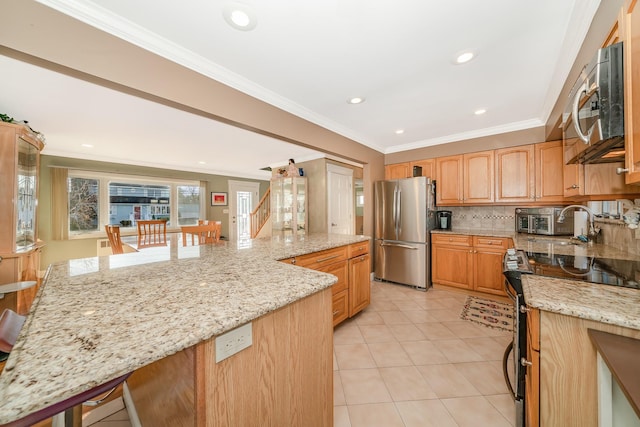 kitchen with light stone counters, ornamental molding, a breakfast bar area, and stainless steel appliances