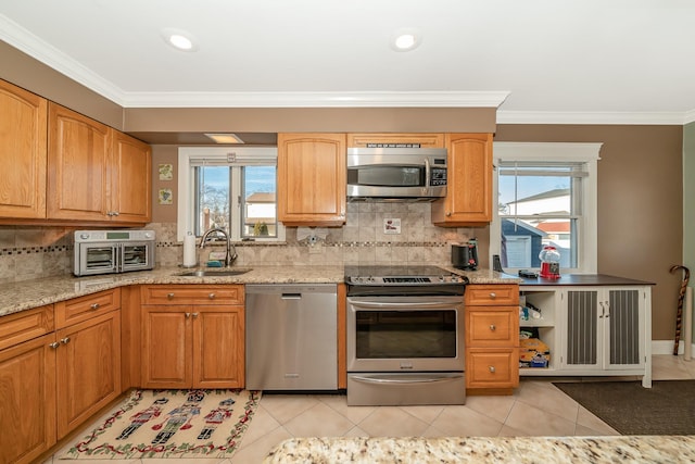 kitchen with light stone counters, sink, ornamental molding, and stainless steel appliances