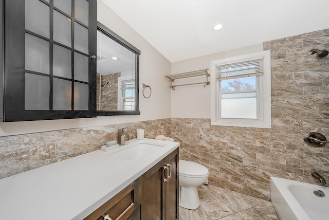 bathroom with vanity, toilet, tile walls, and a wealth of natural light