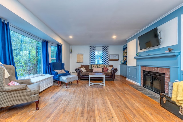 living room with a brick fireplace, a baseboard radiator, and hardwood / wood-style floors