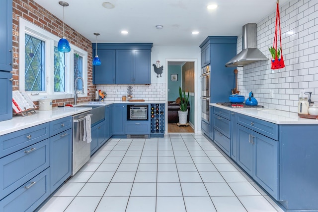 kitchen featuring light tile patterned flooring, wall chimney exhaust hood, sink, decorative light fixtures, and appliances with stainless steel finishes