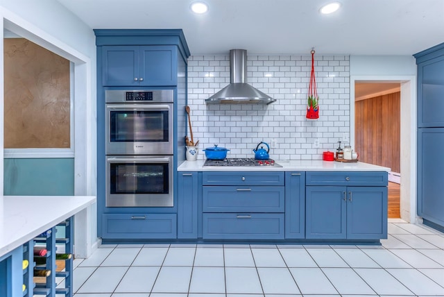 kitchen featuring tasteful backsplash, stainless steel appliances, light tile patterned floors, and wall chimney range hood