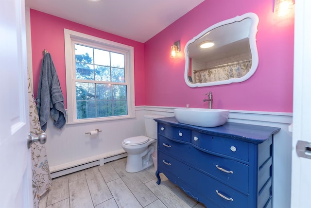 bathroom featuring vanity, a baseboard heating unit, hardwood / wood-style floors, and toilet