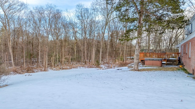 yard covered in snow with a hot tub and a wooden deck