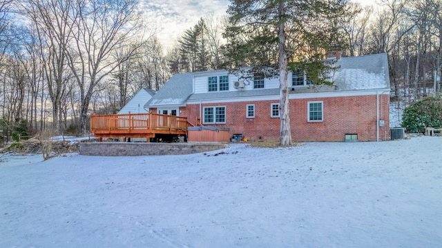 snow covered property with a hot tub, a deck, and central air condition unit