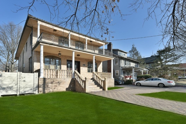 view of front of home with a porch, a balcony, and a front lawn