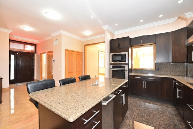 kitchen featuring a kitchen island, a kitchen breakfast bar, dark brown cabinetry, stainless steel appliances, and crown molding