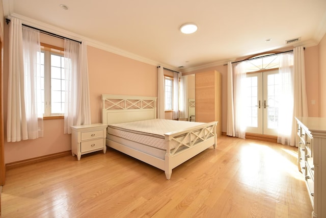 bedroom with crown molding, light hardwood / wood-style flooring, and french doors