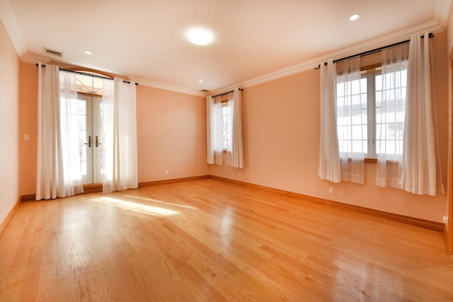 unfurnished room with crown molding, light wood-type flooring, and french doors