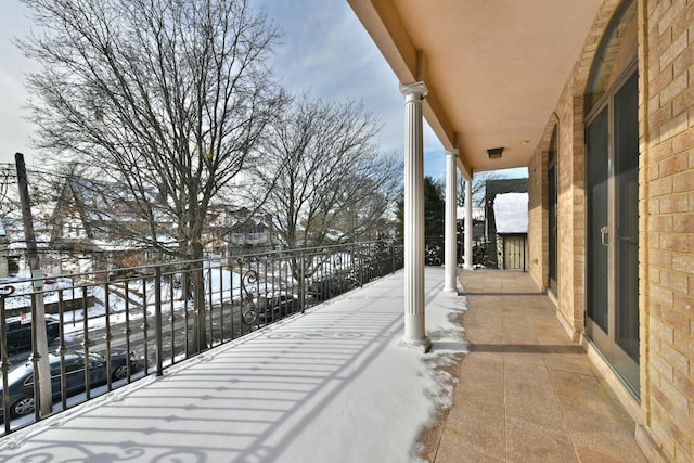 snow covered patio featuring a balcony