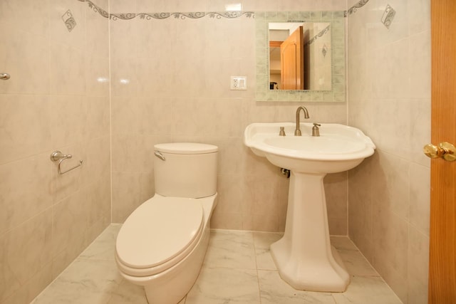 bathroom with toilet and tile walls