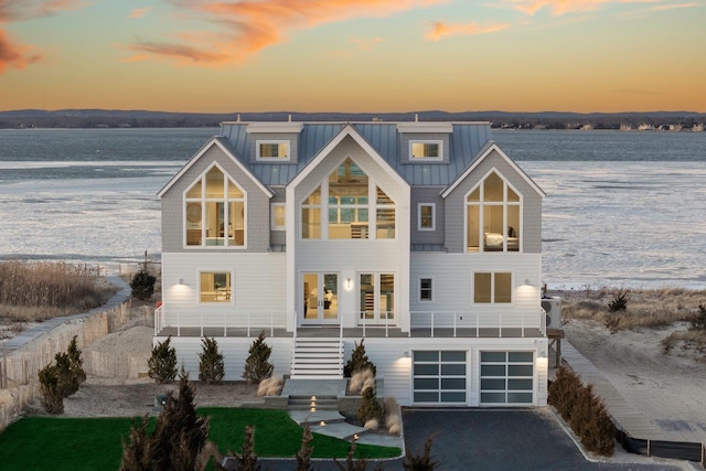 back house at dusk with a garage and a water view