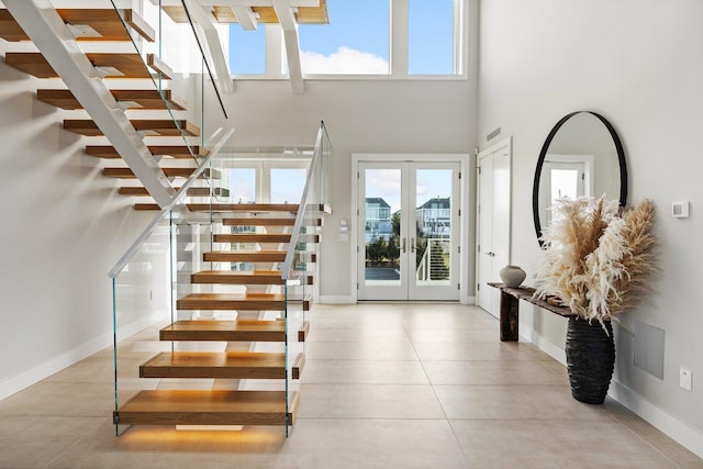 tiled entryway featuring a towering ceiling, french doors, and a wealth of natural light