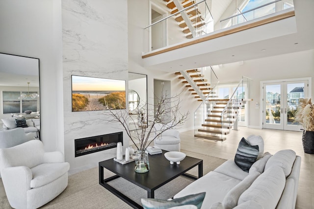 living room with a high ceiling, french doors, and a high end fireplace