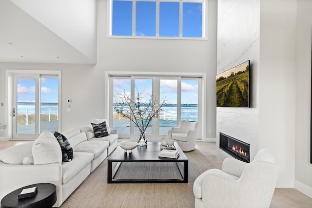 living room with a high ceiling, a fireplace, and a water view