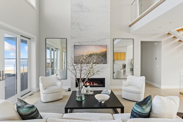 living room featuring a high ceiling, a high end fireplace, and a healthy amount of sunlight