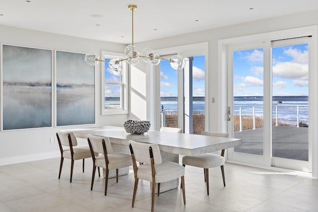 tiled dining room with a healthy amount of sunlight, a notable chandelier, and a water view