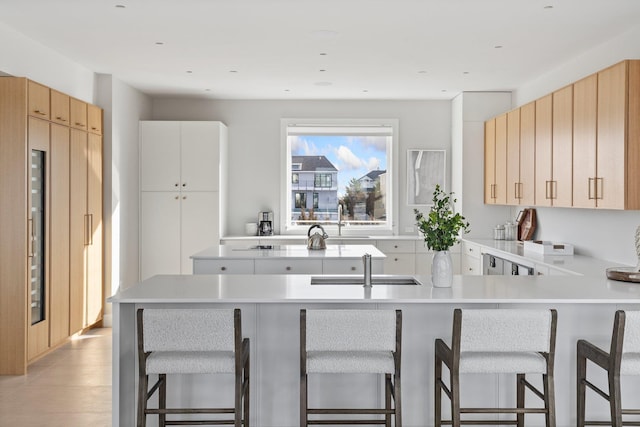 kitchen with sink, kitchen peninsula, a kitchen breakfast bar, and light brown cabinets