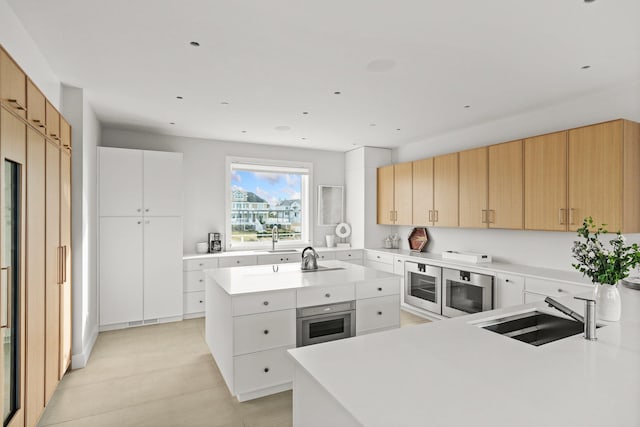 kitchen featuring sink, a center island, oven, and white cabinetry