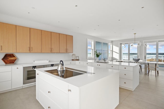 kitchen featuring pendant lighting, a center island, oven, black electric stovetop, and white cabinets