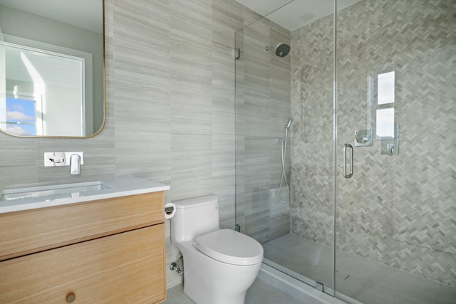 bathroom featuring toilet, a shower with door, vanity, and tile walls