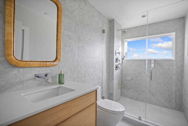 bathroom with tile walls, a shower with door, toilet, and vanity