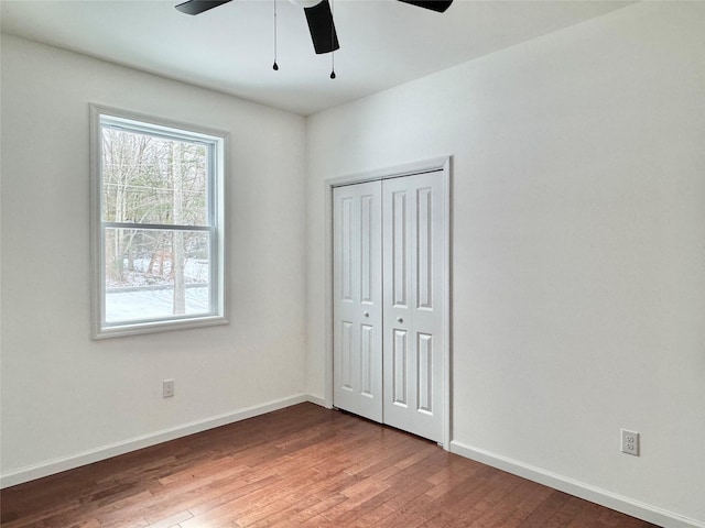 unfurnished bedroom featuring ceiling fan, a closet, and hardwood / wood-style floors