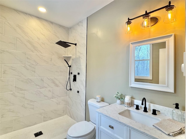 bathroom featuring toilet, vanity, and tiled shower