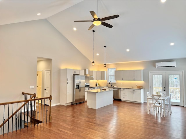 kitchen featuring a center island, stainless steel appliances, a healthy amount of sunlight, a wall unit AC, and high vaulted ceiling