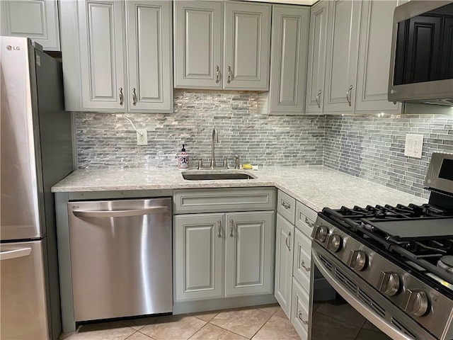 kitchen with stainless steel appliances, light tile patterned floors, sink, and tasteful backsplash