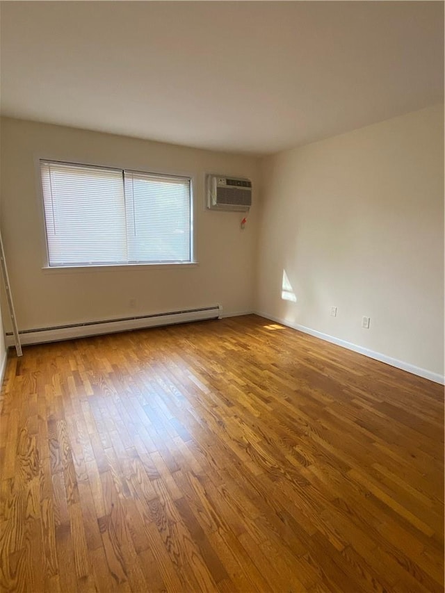 empty room with an AC wall unit, baseboard heating, and hardwood / wood-style flooring