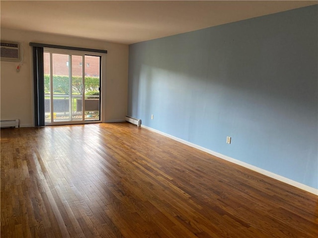 spare room featuring a baseboard radiator, a wall mounted air conditioner, and wood-type flooring