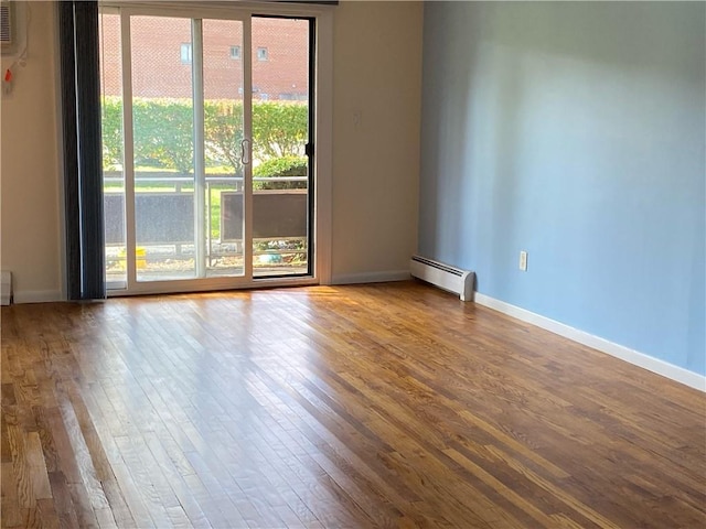 empty room with a baseboard heating unit, hardwood / wood-style floors, and a wealth of natural light