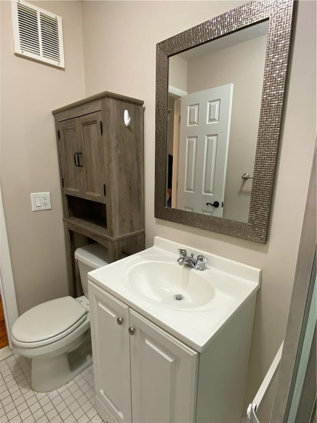 bathroom with toilet, vanity, and tile patterned flooring