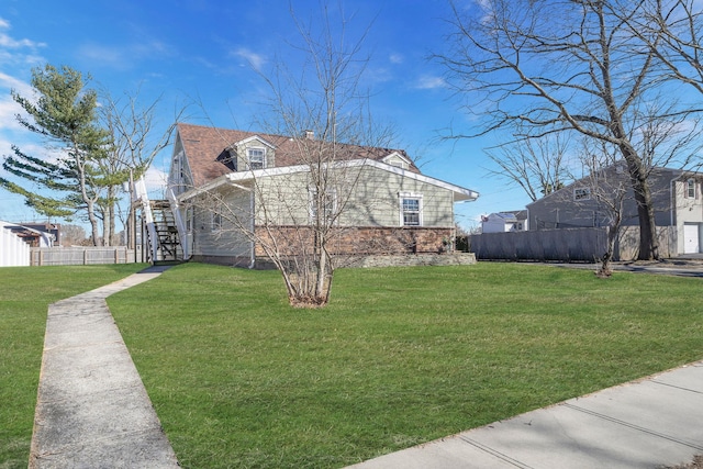 view of property exterior with stairway, a yard, and fence