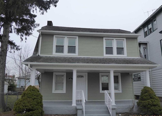 view of front of home featuring a porch, a shingled roof, a chimney, and fence