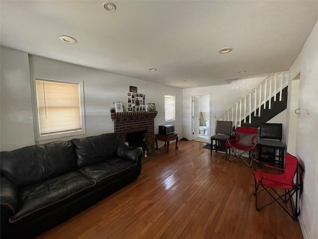 living room featuring recessed lighting, wood-type flooring, a fireplace, and stairway