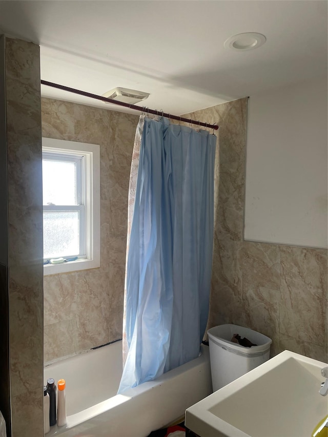bathroom with visible vents and shower / bathtub combination with curtain