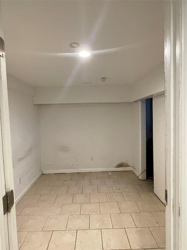 finished below grade area featuring light tile patterned floors and baseboards