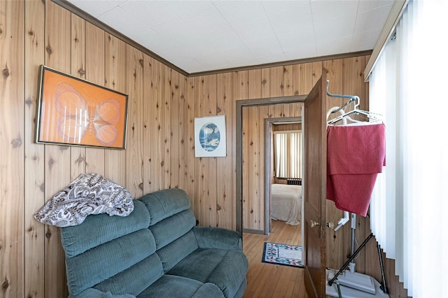 living area with hardwood / wood-style floors, wooden walls, and crown molding