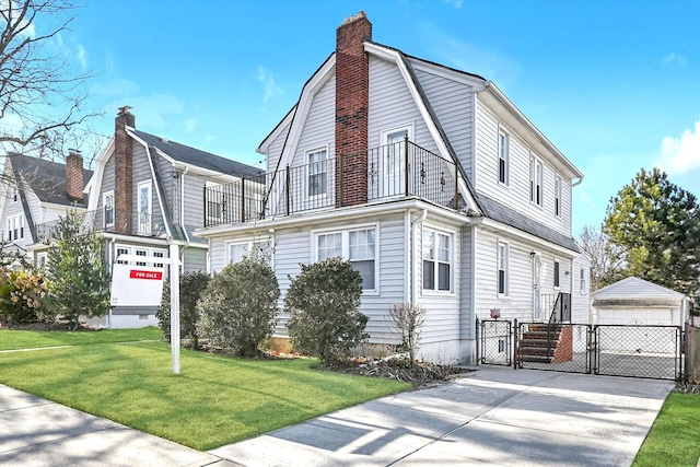 view of front of house featuring a front yard, a balcony, a garage, and an outdoor structure