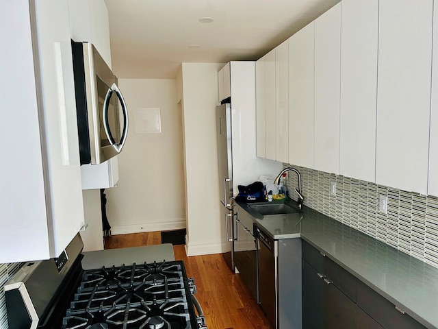 kitchen with stainless steel appliances, sink, dark hardwood / wood-style floors, white cabinets, and tasteful backsplash